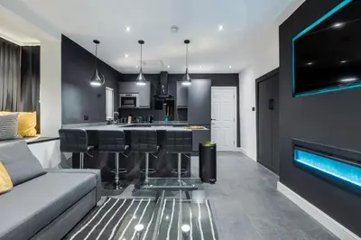 a kitchen and living room with a bar with stools at TWO BED Modern Apartment 5min walk to Town centre with Free Parking ! Under New Management in Blackpool