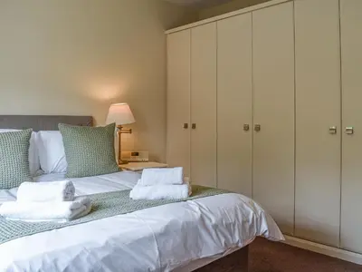 a bedroom with a large bed with white cabinets at 8 Lowther Gardens in Grange Over Sands