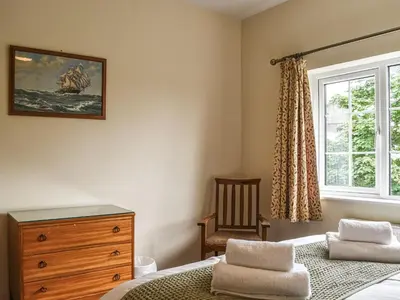a bedroom with a bed and a dresser and a window at 8 Lowther Gardens in Grange Over Sands