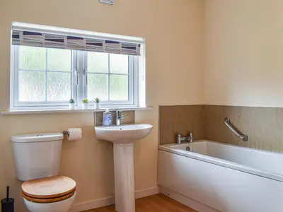 a bathroom with a toilet and a sink and a bath tub at 8 Lowther Gardens in Grange Over Sands