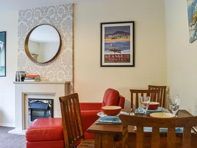 a dining room with a table and chairs and a mirror at 8 Lowther Gardens in Grange Over Sands