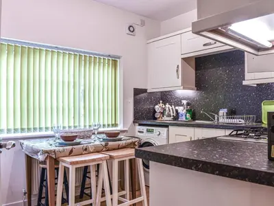 a kitchen with white cabinets and a black counter top at 8 Lowther Gardens in Grange Over Sands