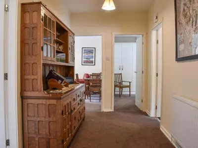 a hallway with a large wooden cabinet and a dining room at 8 Lowther Gardens in Grange Over Sands