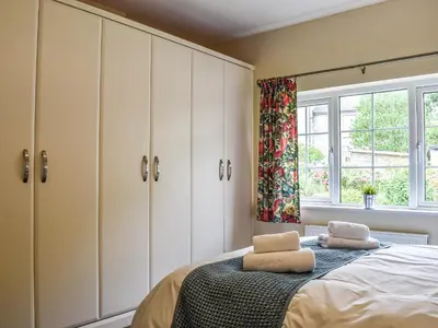 a bedroom with white cabinets and a bed with two towels at 8 Lowther Gardens in Grange Over Sands