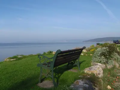 a bench sitting on a grassy hill overlooking the water at Shore Cottage in Silverdale