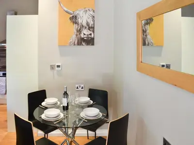 a dining room with a table with a cow picture on the wall at Beckside House in Dalton in Furness