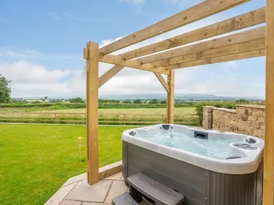 a hot tub on a patio with a wooden pergola at Dewhurst Farm in Langho