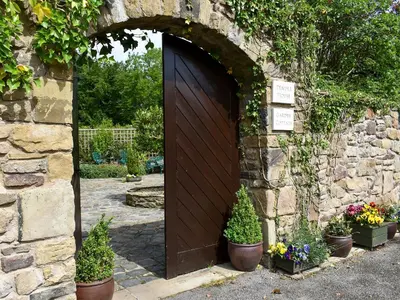 a wooden door in a stone wall with potted plants at Garden Cottage in Sabden