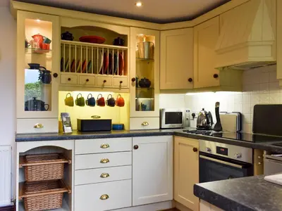 a kitchen with white cabinets and a counter at Garden Cottage in Sabden
