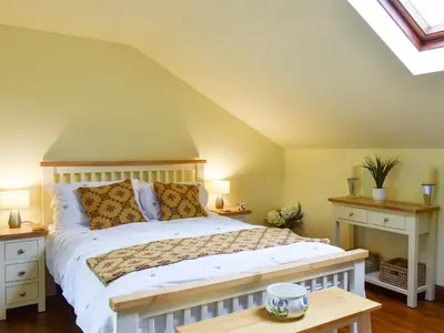 a bedroom with a large bed and two night stands at Garden Cottage in Sabden