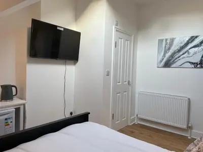 a bedroom with a bed with a flat screen tv on the wall at CityStays Rooms with Free Parking in Liverpool