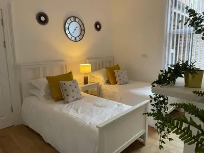 two beds in a room with a clock on the wall at CityStays Rooms with Free Parking in Liverpool