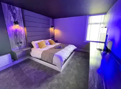 a purple bedroom with a bed and a window at BREEZE SUITES - LUXURY GROUP ACCOM - SLEEPS 19 in Blackpool