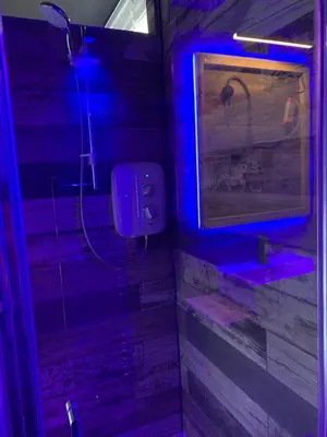 a bathroom with a shower with a blue light at BREEZE SUITES - LUXURY GROUP ACCOM - SLEEPS 19 in Blackpool