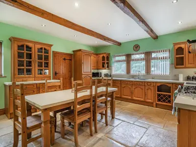a kitchen with wooden cabinets and a table and chairs at Highfield Cottage in Poulton le Fylde