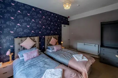 a bedroom with two beds and a wall with pink butterflies at Blackpool Abode - The Cinema House in Blackpool