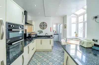 a kitchen with white cabinets and black counter tops at Blackpool Abode - The Cinema House in Blackpool