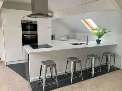 a kitchen with a counter with stools and a sink at Lovely 2 bedroom modern loft apartment sea view in Morecambe