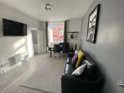 a living room with a black leather couch and a table at Blackpool Abode - 124 Elite Apartments in Blackpool