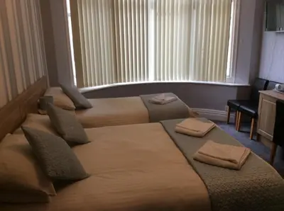 a hotel room with three beds with towels on them at Beaucliffe continental in Blackpool