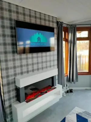 a living room with a tv above a fireplace at 4 Bed Luxury Lodge with Hot tub near Lake District in Warton