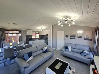 a living room with blue couches and a kitchen at 4 Bed Luxury Lodge with Hot tub near Lake District in Warton