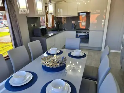 a dining room table with white chairs and a kitchen at 4 Bed Luxury Lodge with Hot tub near Lake District in Warton
