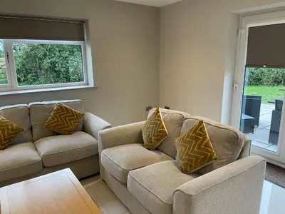 a living room with two couches and a table at Lux Cottage in Blackburn