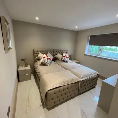 a bedroom with a large bed with two pillows at Lux Cottage in Blackburn