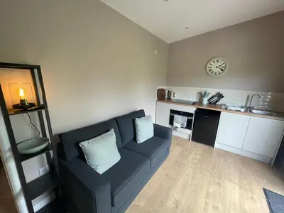 a living room with a couch and a clock on the wall at Beautiful self-catering cottages, Ribble Valley in West Bradford