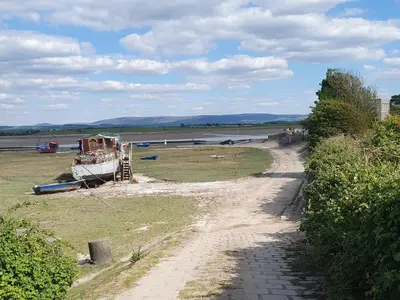 a dirt road next to a field with a boat at Marrion House in Middleton