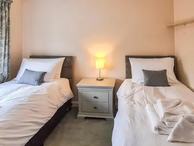 two beds in a bedroom with a lamp on a night stand at Marrion House in Middleton