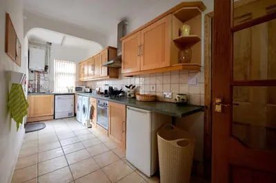 a kitchen with wooden cabinets and a tile floor at Contractors and Pets Welcome, Only 2 miles from M57, M58, Whole House Rental Sleeps 4 to 9, Short Walk to Orrell Station in Liverpool