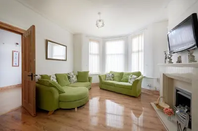 a living room with two green chairs and a fireplace at Contractors and Pets Welcome, Only 2 miles from M57, M58, Whole House Rental Sleeps 4 to 9, Short Walk to Orrell Station in Liverpool