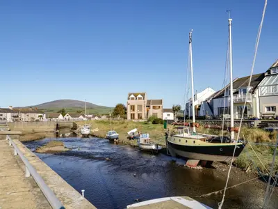 a boat is docked in a river with houses at Harbour View in Millom