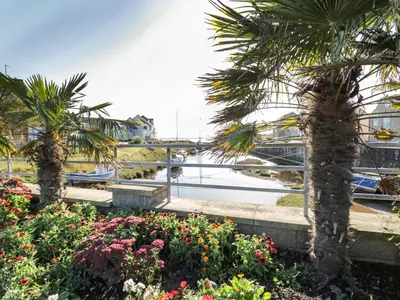 a garden with palm trees and flowers in front of a marina at Harbour View in Millom