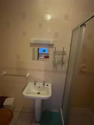 a small bathroom with a sink and a shower at Highbury Hotel in Blackpool