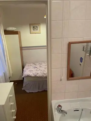 a bathroom with a sink and a mirror and a bed at Highbury Hotel in Blackpool