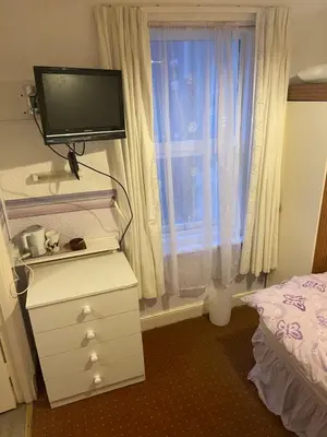a bedroom with a tv on a dresser and a window at Highbury Hotel in Blackpool
