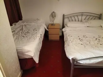 two twin beds in a room with a lamp on a night stand at Highbury Hotel in Blackpool