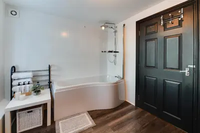 a bathroom with a white tub and a black door at InstaLet Apartments I Wigan Central I Free Parking in Wigan