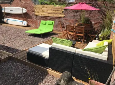a patio with green furniture and a table and an umbrella at The Beach House South - Blackpool - Entire Holiday Home in Blackpool