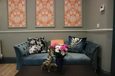 a blue couch with a vase of flowers on a table at No 9 The Folly in Southport