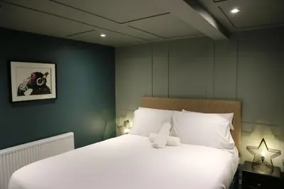 a bedroom with a large bed with white sheets at No 9 The Folly in Southport
