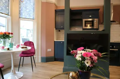 a kitchen and dining room with a table and flowers at No 9 The Folly in Southport