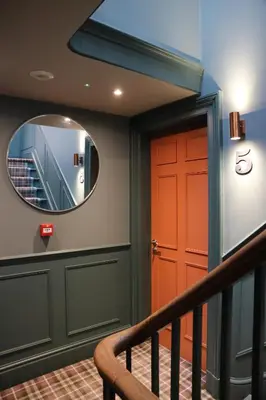 a hallway with a red door and a mirror at No 9 The Folly in Southport