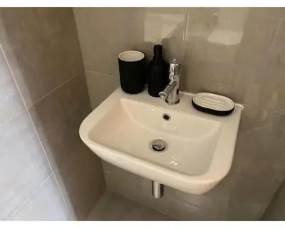 a white sink in a bathroom with two bottles on it at Kempston Suites Liverpool Apartment 1 in Liverpool