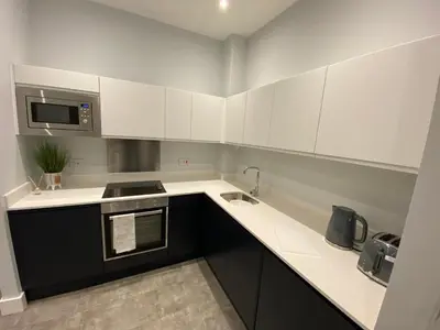 a kitchen with white cabinets and a sink at Kempston Suites Liverpool Apartment 1 in Liverpool