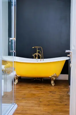 a yellow tub in a bathroom with a black wall at The Eden Warehouse - Gold Apartment, sleeps 6 in Southport