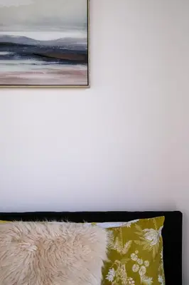 a bed with a pillow and a painting on the wall at The Eden Warehouse - Gold Apartment, sleeps 6 in Southport
